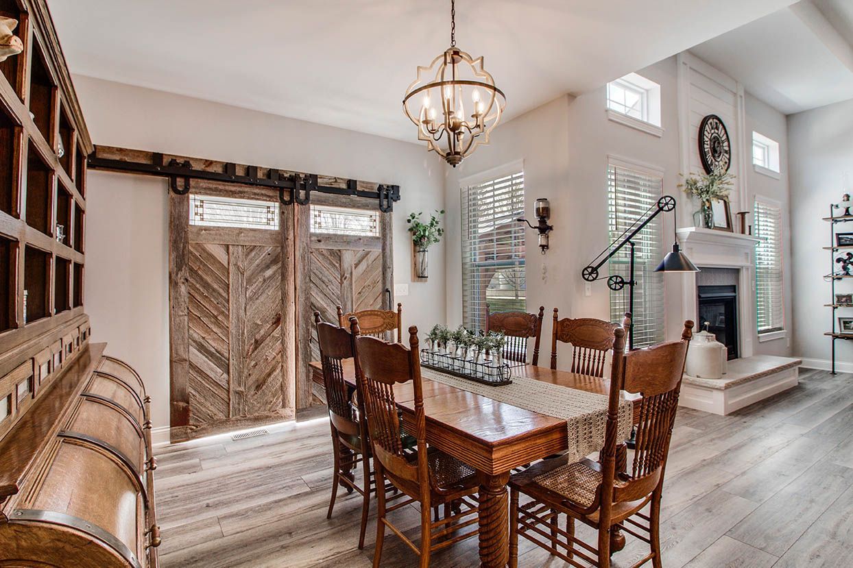 Elegant dining room with rustic wood table, woven chairs, and large barn-style doors