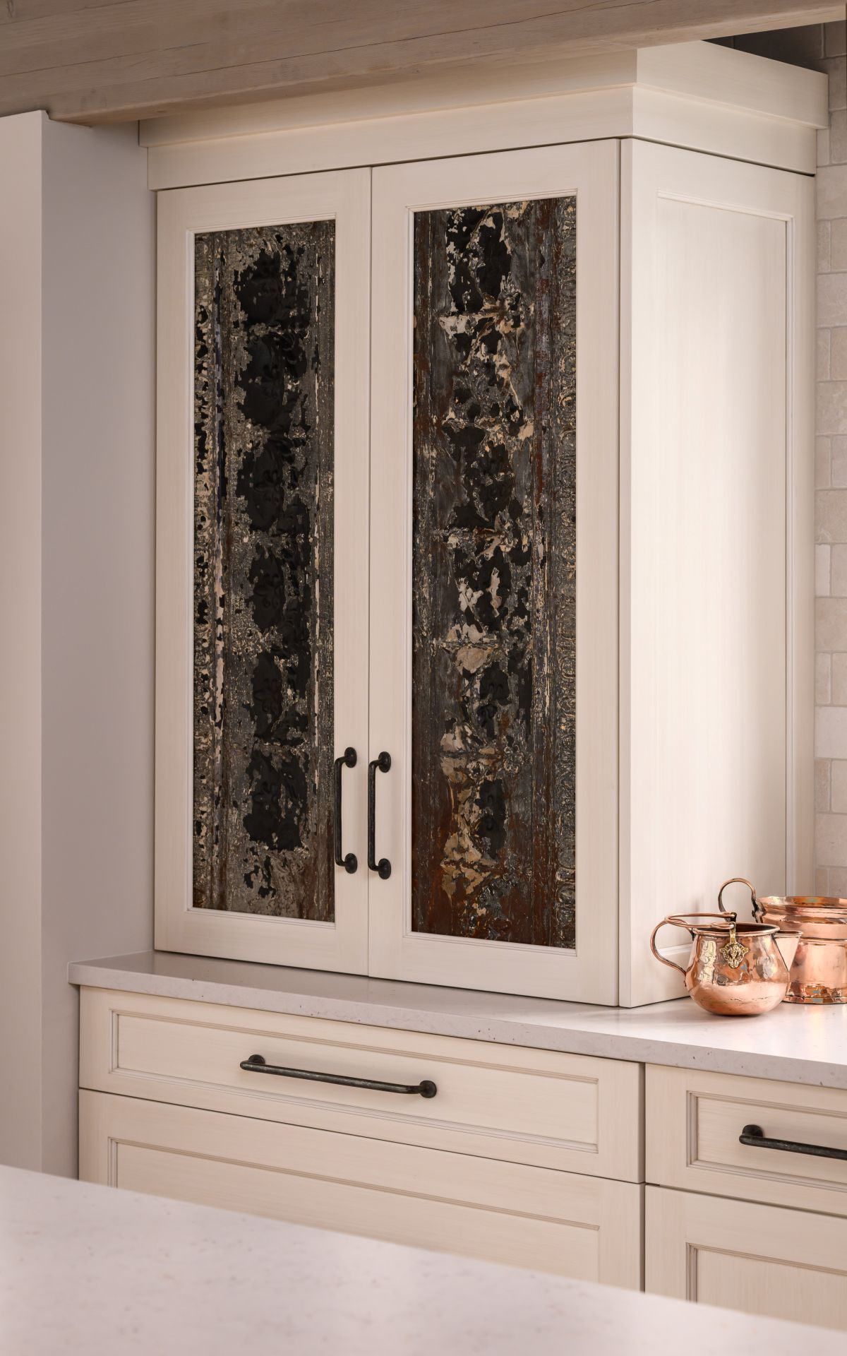 White kitchen cabinet with glass-paneled doors above a countertop and drawers beneath.