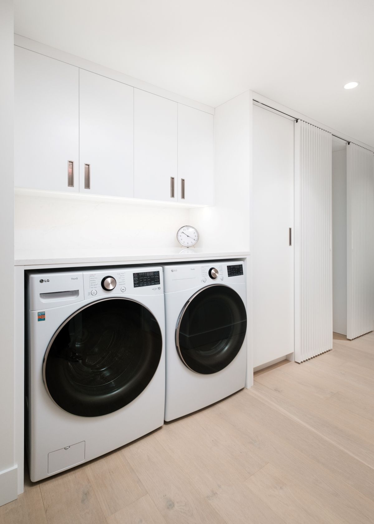 Bright laundry room with white cabinets and side-by-side washer and dryer.