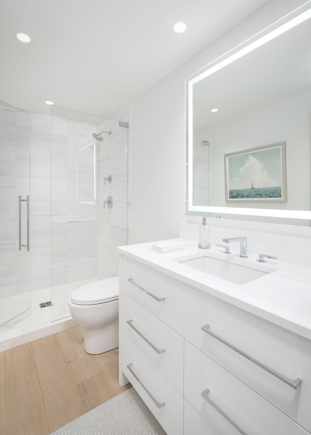 Bright white modern bathroom with glass shower, toilet, and double sink vanity