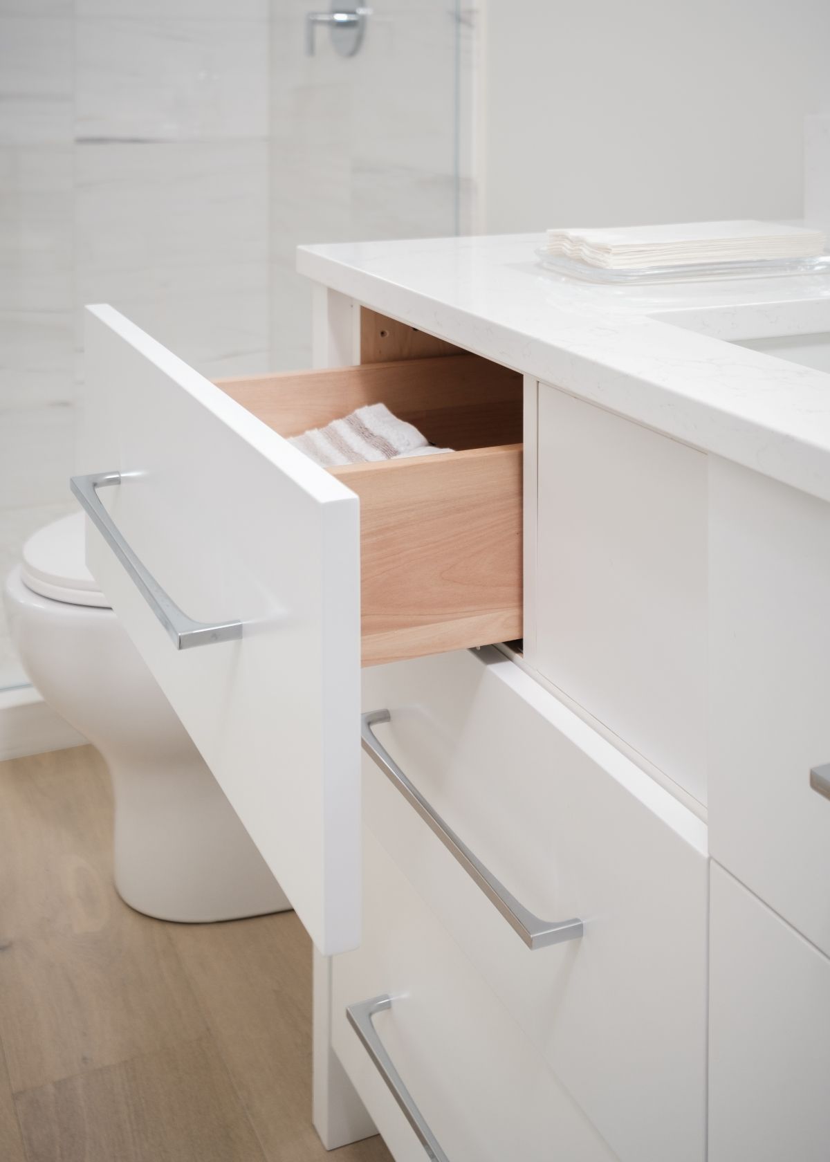 Bathroom vanity with an open drawer showing wood organizer bins and a chrome handle
