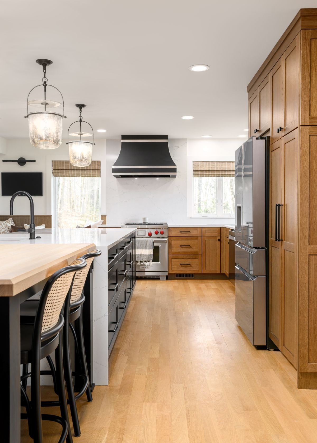 Bright modern kitchen with wood floors, island seating, stainless appliances, and large cabinets