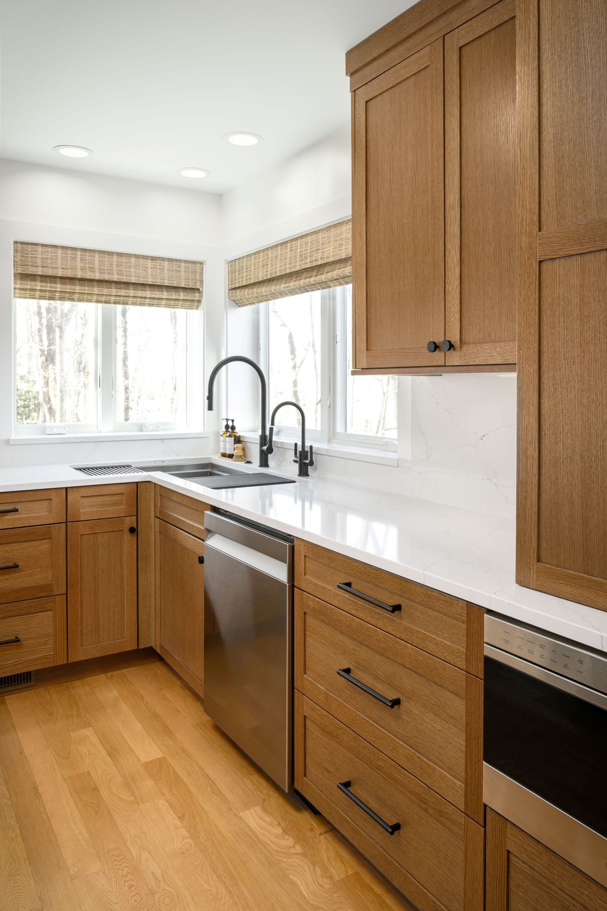 Bright modern kitchen with wood cabinets, white countertops, stainless sink, and hardwood floors