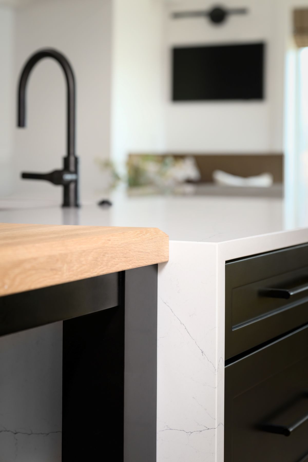 Modern kitchen island with black faucet, wood countertop, and white marble side panel