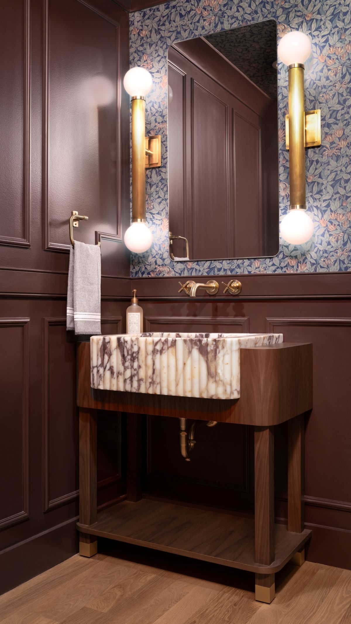 Elegant dark wood bathroom vanity with mirror, sconces, and marble countertop in a warmly lit room