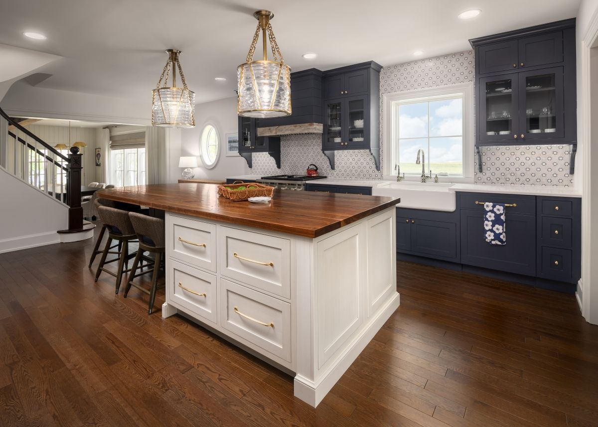 Modern kitchen with large island, dark cabinets, wood floors, and pendant lights