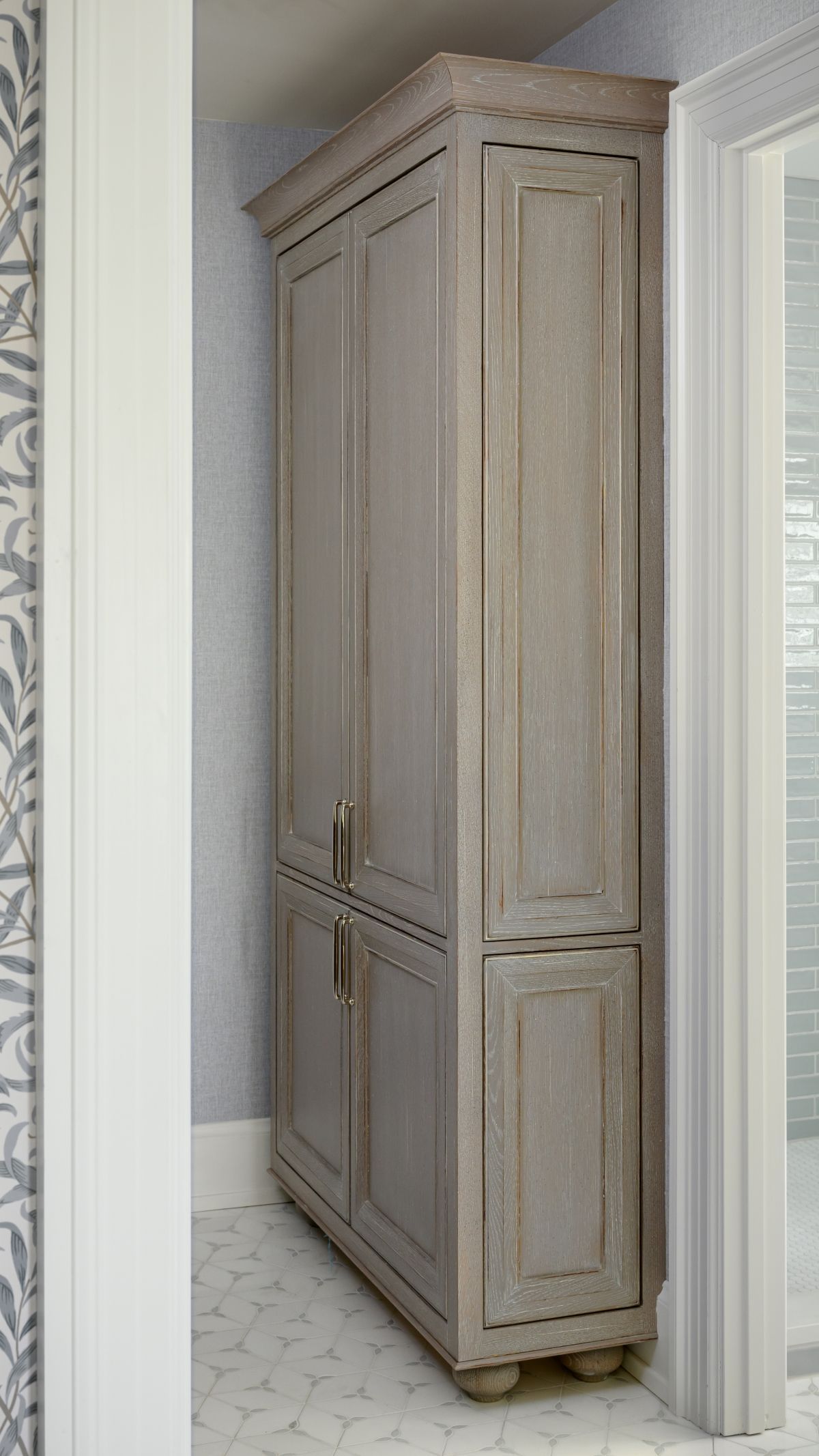Tall weathered gray cabinet in a narrow hallway beside a white doorway.