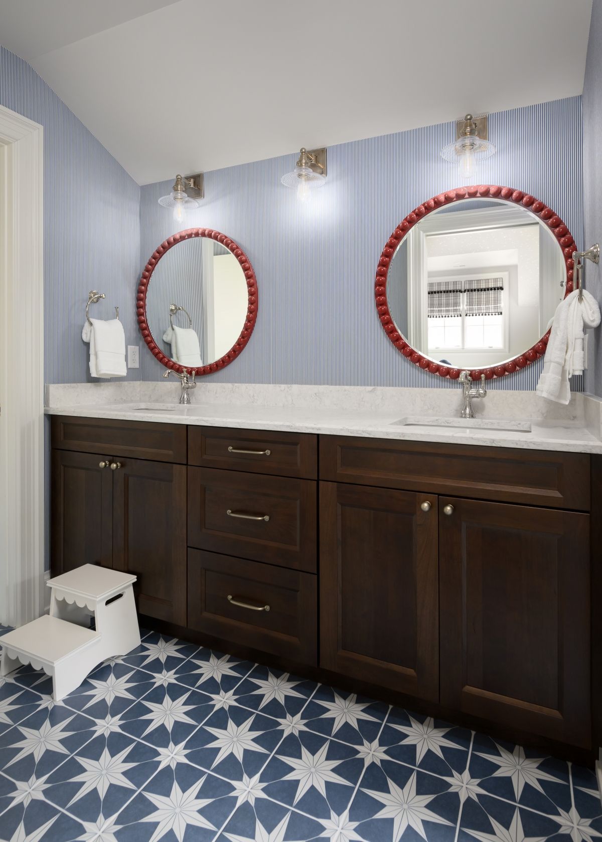 Bathroom vanity with dark wood cabinets, double round mirrors, and blue star-patterned floor tiles