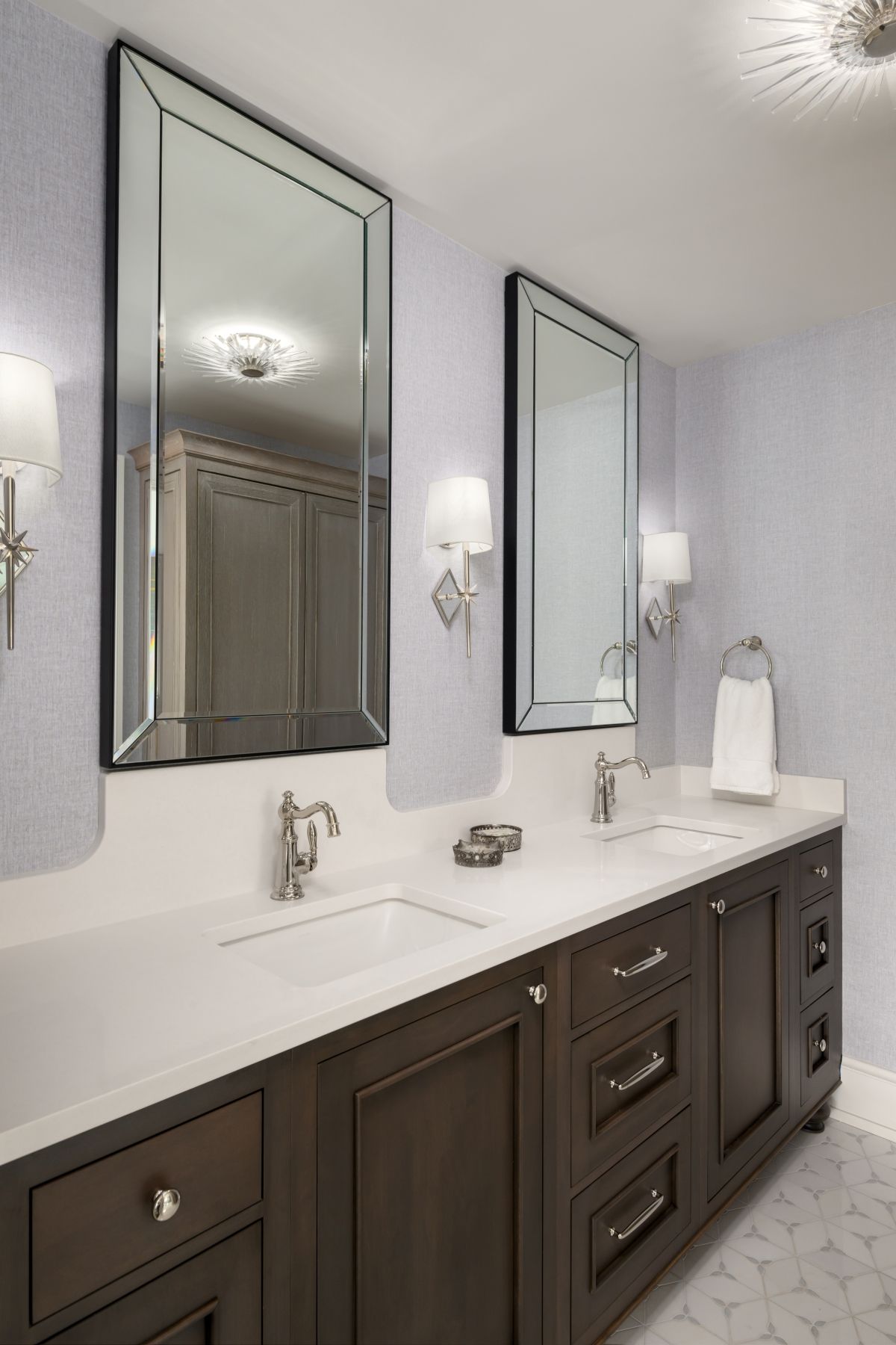 Elegant bathroom vanity with dark wood cabinets, white countertop, and large wall mirrors.