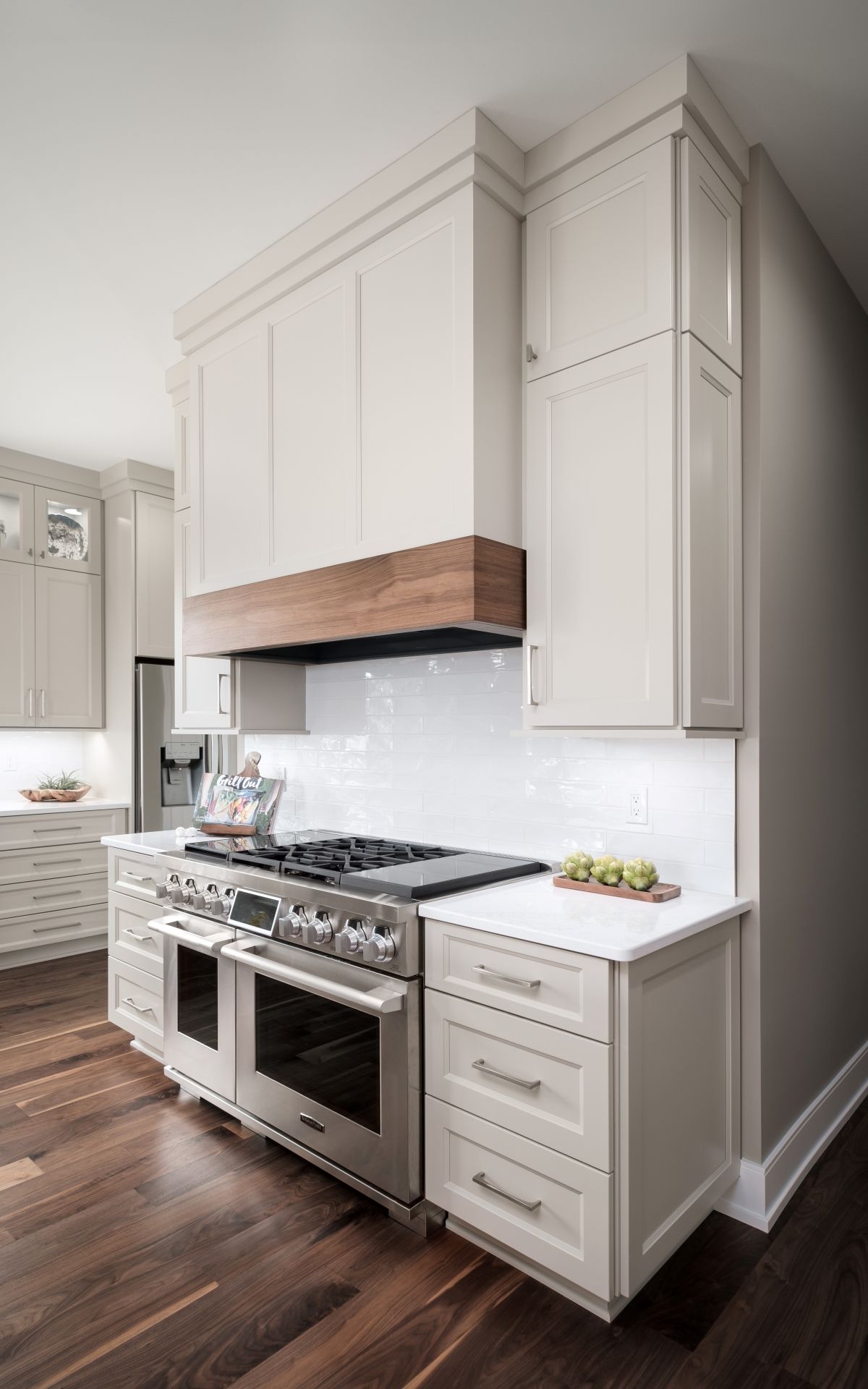 Bright modern kitchen with white cabinets, gas range, and dark wood floors