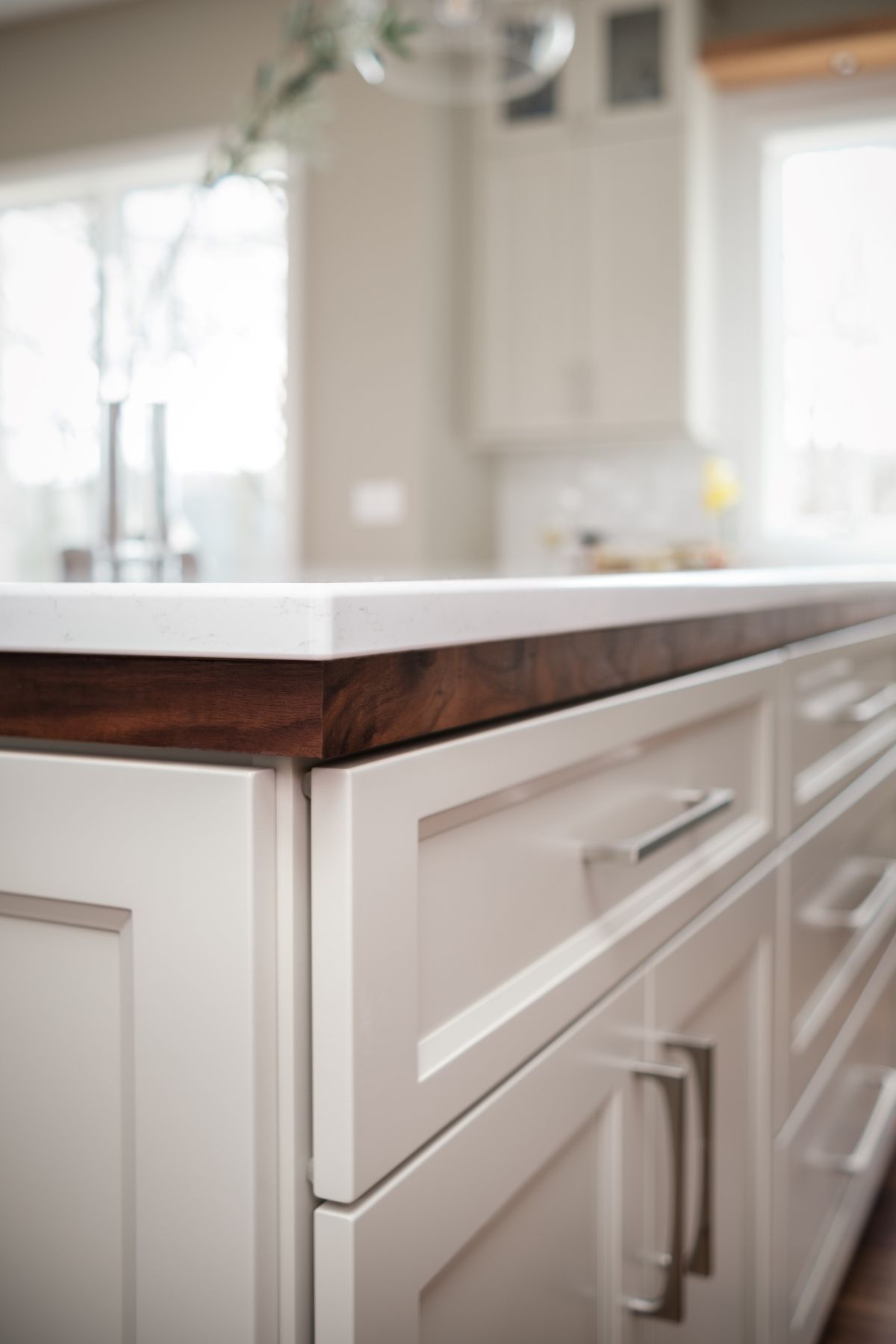 White kitchen cabinets with a dark wood countertop and stainless steel handles in a bright interior