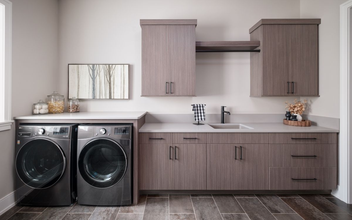 Laundry room with gray cabinets, sink, countertop, and two front-loading washers/dryers