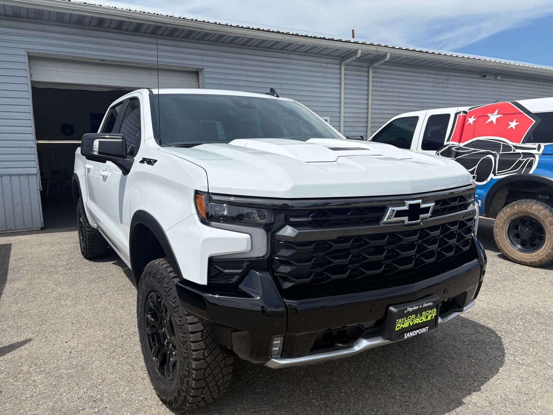 White Chevrolet pickup truck parked outside a building with black rims.