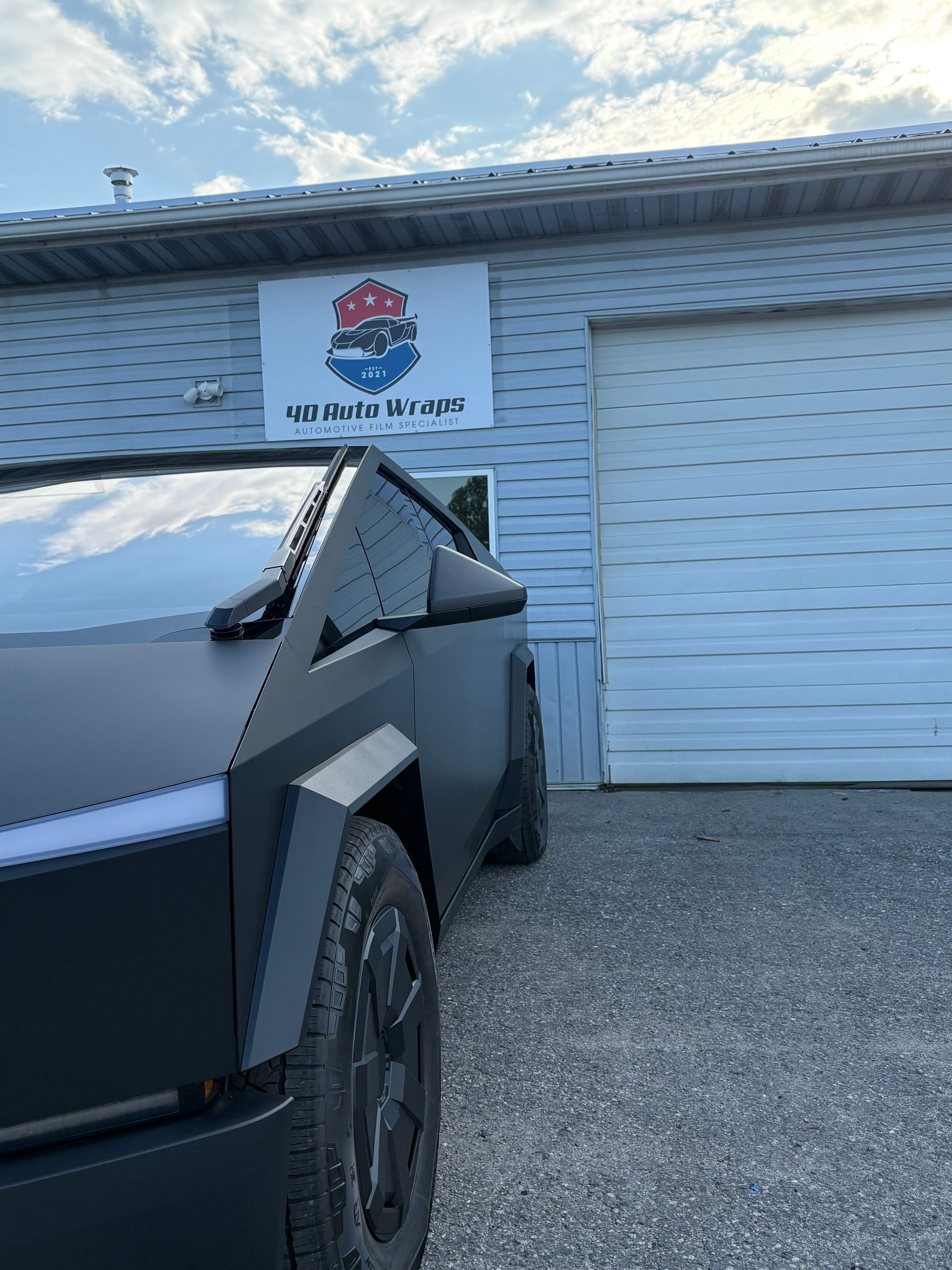 Tesla Cybertruck parked outside a building with a sign.
