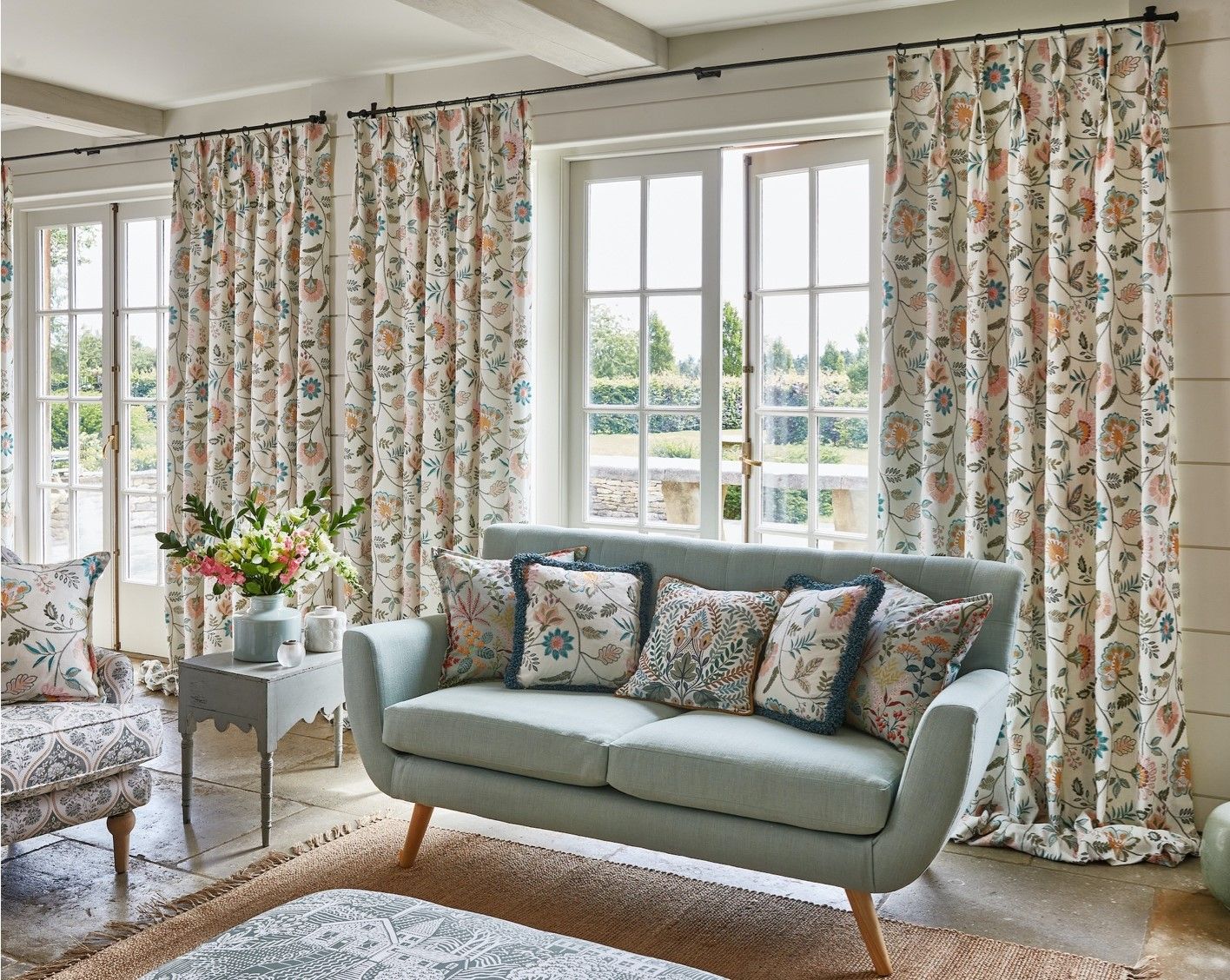 A living room with a couch , chair , table and curtains.