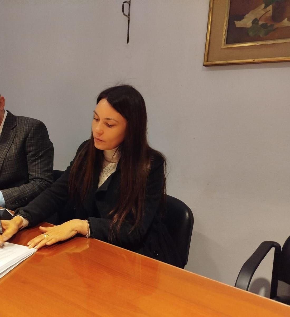 Mujer sentada en una mesa de conferencias, mirando unos papeles durante una reunión.