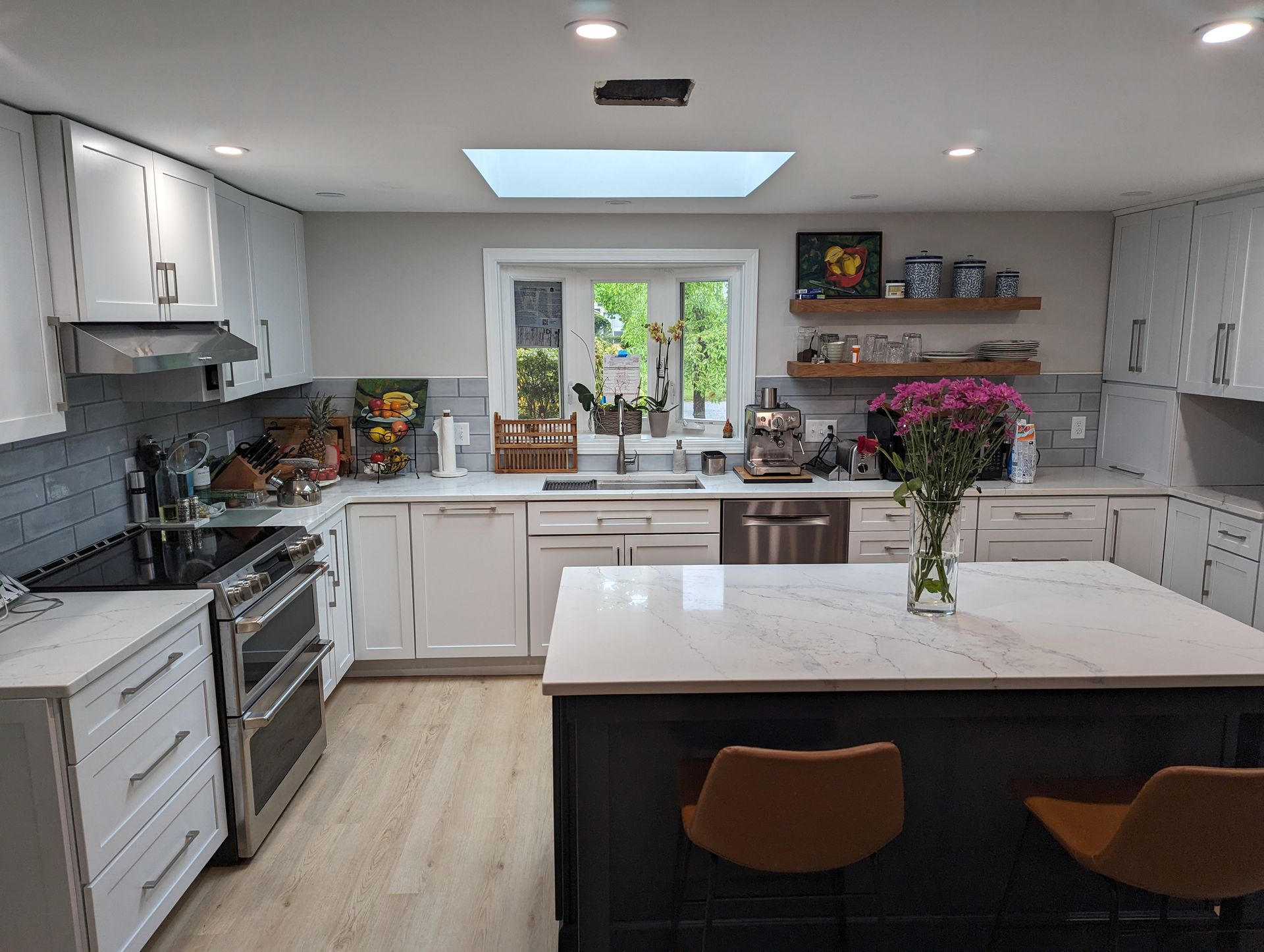 A kitchen with white cabinets and stainless steel appliances and a large island.