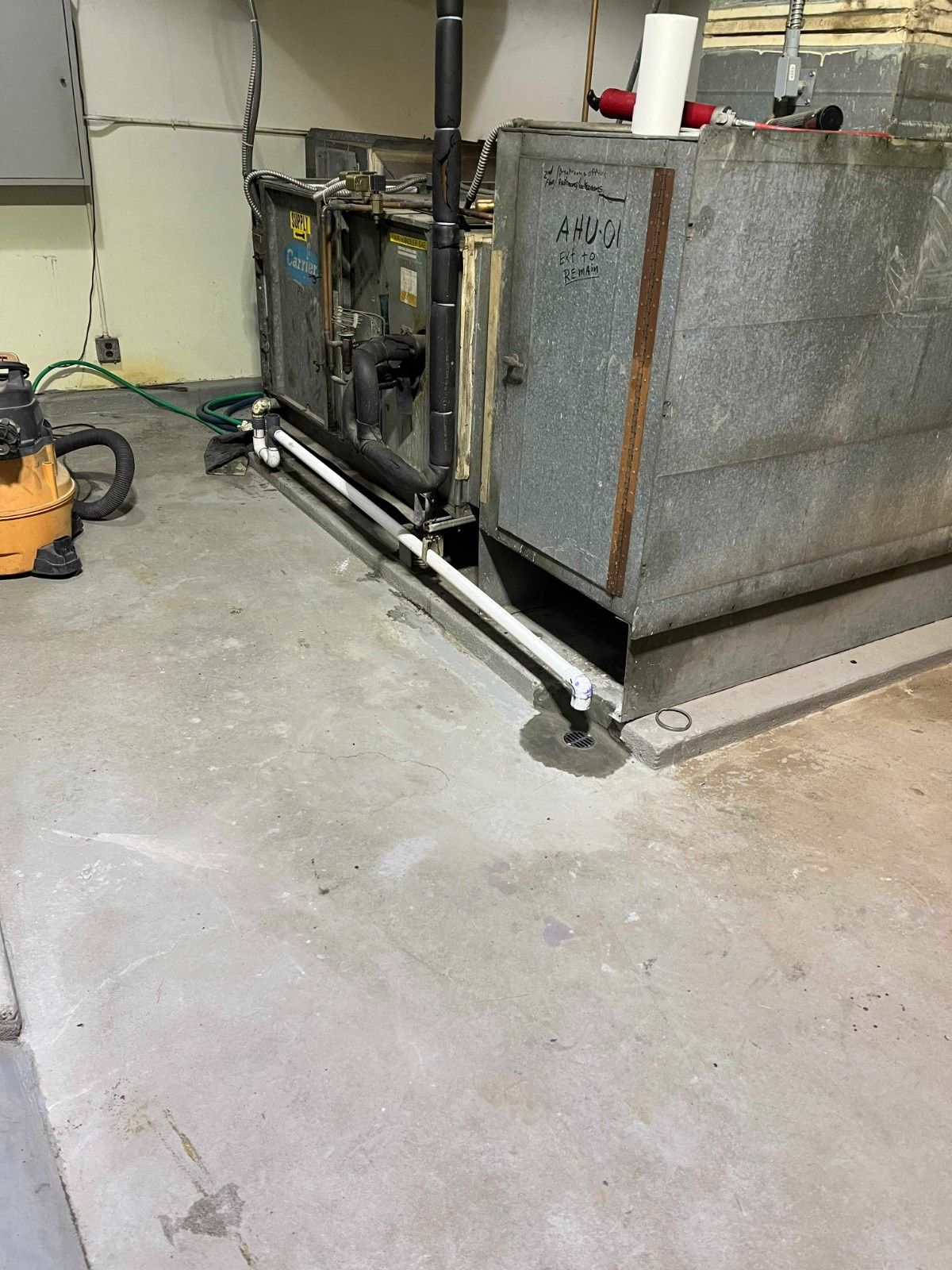 HVAC system in a basement featuring a metal cabinet, electrical components, and a white PVC condensate drain pipe.
