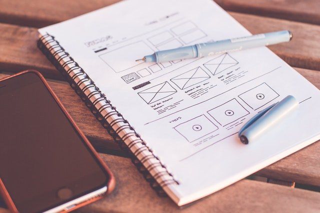 a notebook with a cell phone and pens on it