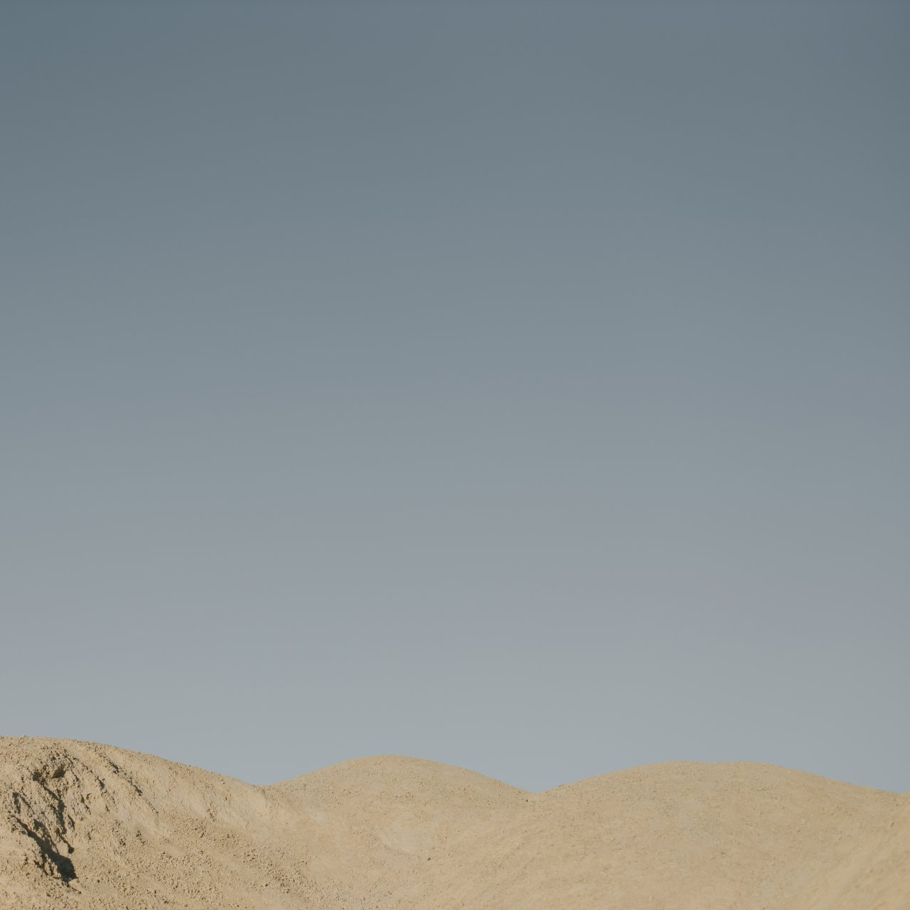 Sandy dunes beneath a clear pale blue sky