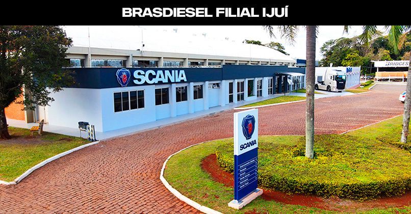 A concessionária Brasdiesel Scania em Ijuí, com seu prédio branco com detalhes em azul, entrada pavimentada e paisagismo.