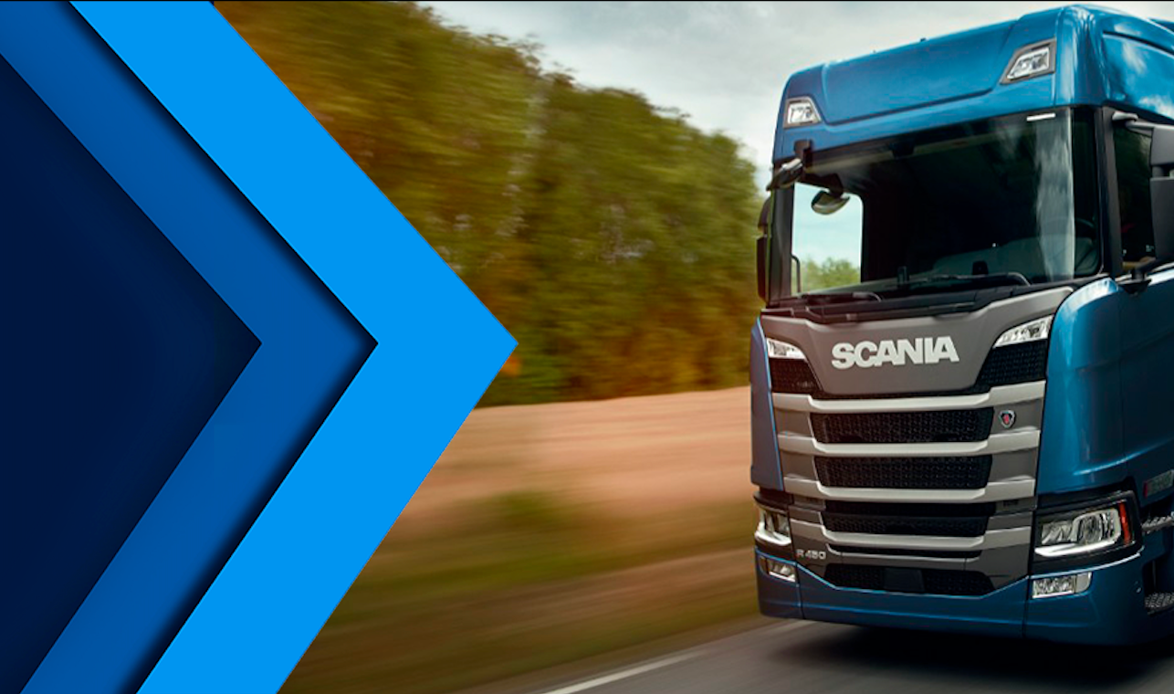 Um caminhão Scania azul trafegando em uma estrada ao lado de um campo, com um chamativo desenhdo