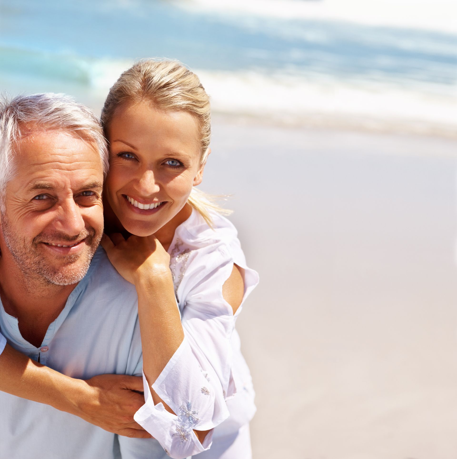 Smiling couple outdoors, woman leaning on man’s shoulder in soft sunlight