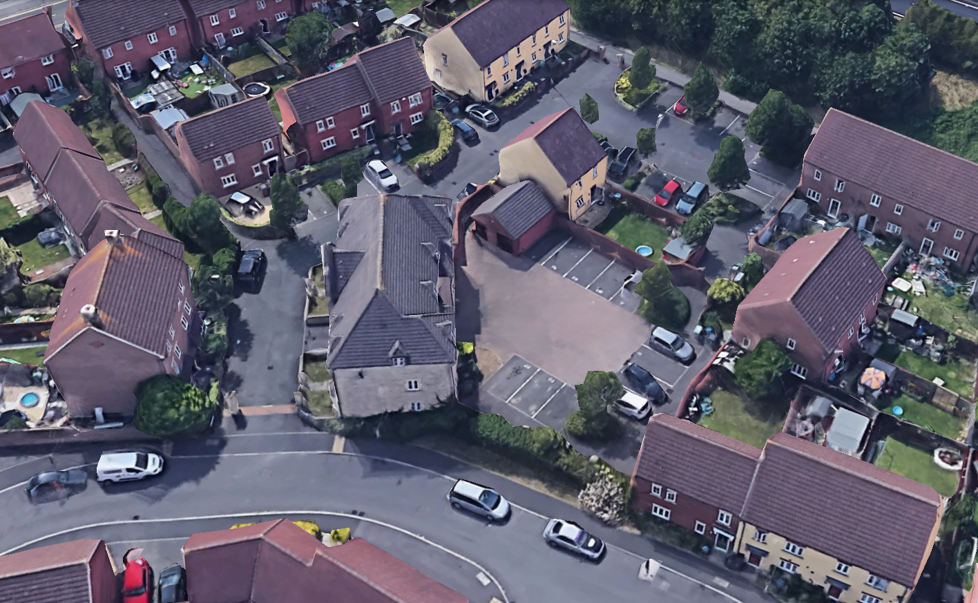 An aerial view of a residential neighborhood with brick houses, small parking lots, and parked cars on quiet streets.
