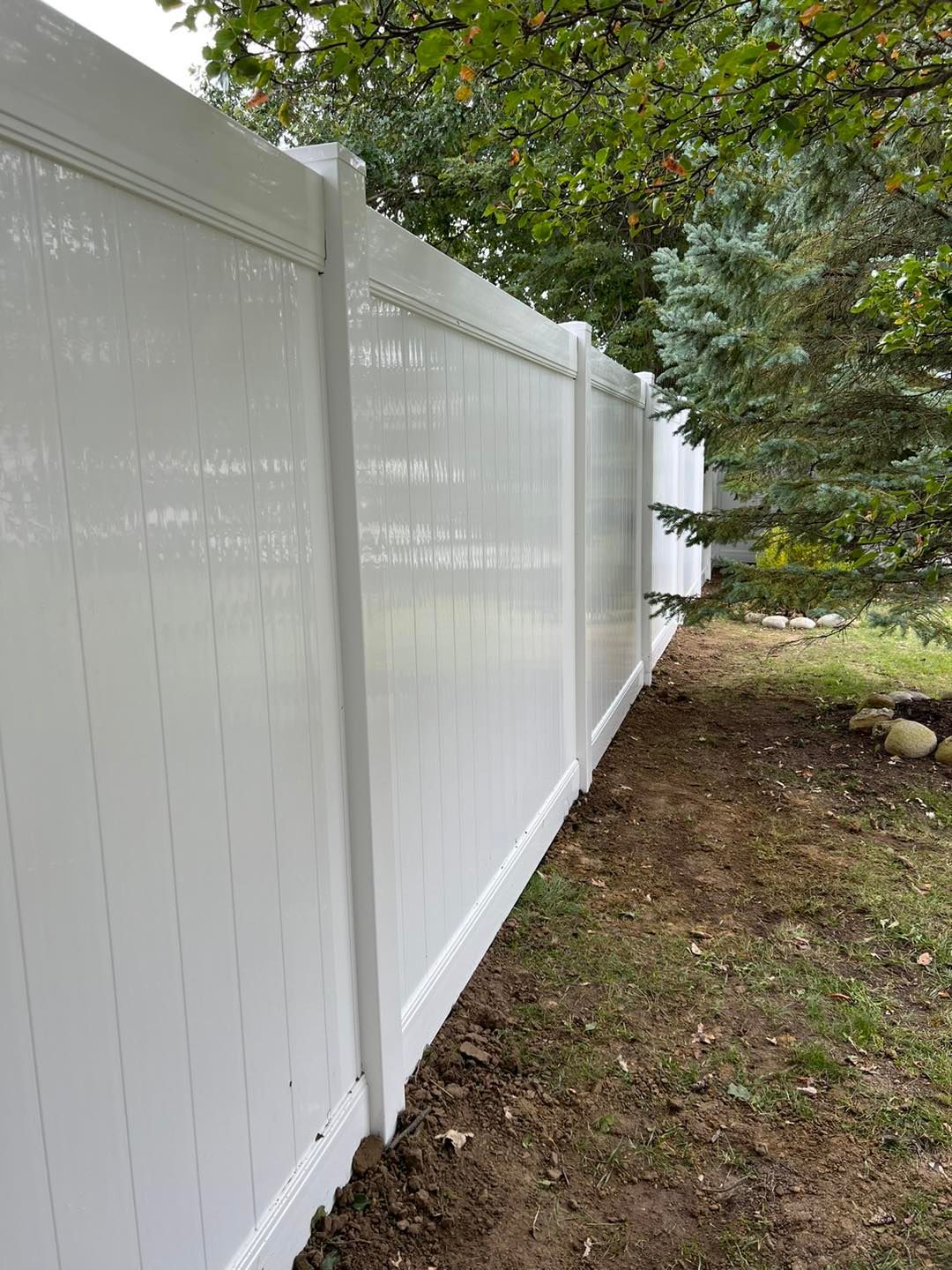 a white fence with trees in the background.