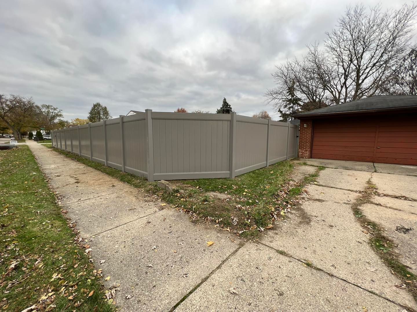 a gray fence surrounds the corner of a driveway.