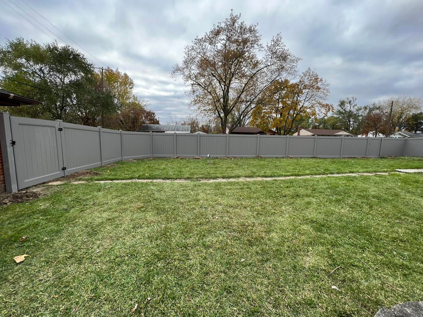 a gray fence surrounds a lush green yard.