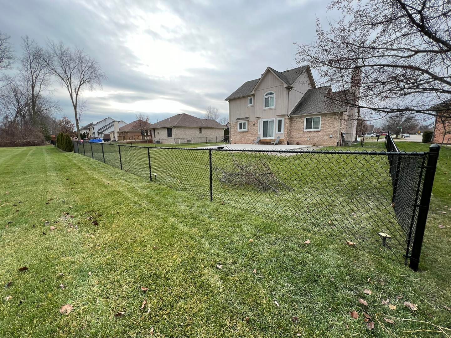 a chain link fence surrounds the backyard of a house.