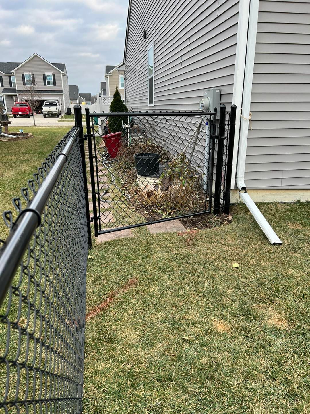 a chain link fence with a gate in the backyard of a house.