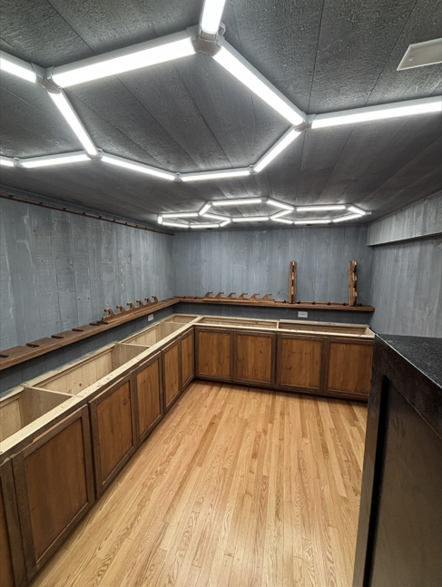 Empty U-shaped kitchen with wood cabinets, gray walls, wood floor, and geometric LED ceiling lights