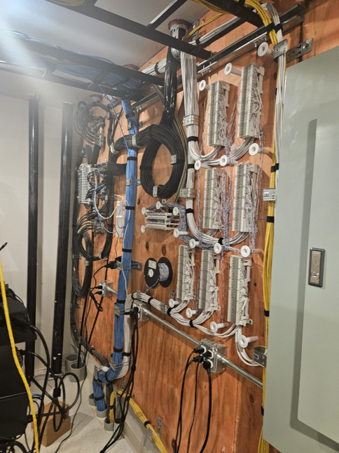 Wall-mounted electrical and networking equipment with cables in a utility room