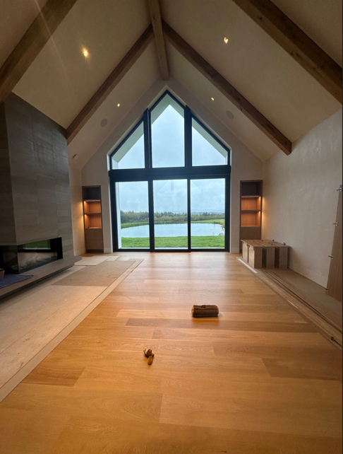 Empty modern living room with vaulted wood ceiling and large windows overlooking water