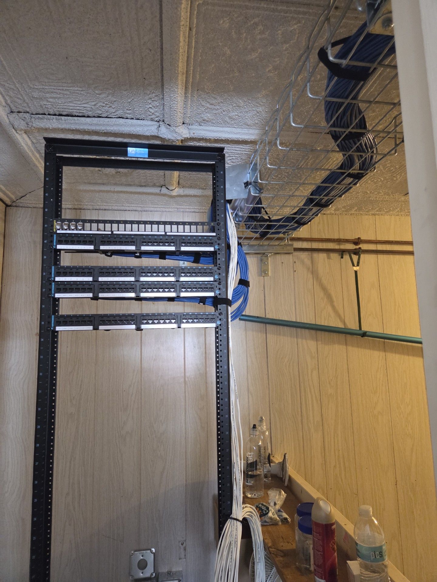Indoor utility room with exposed ceiling, black pipework, and a beige partition wall.