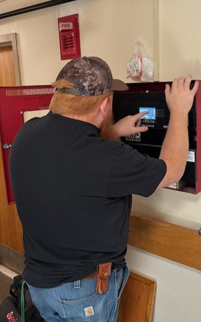 Electrician wiring a commercial fire alarm control panel