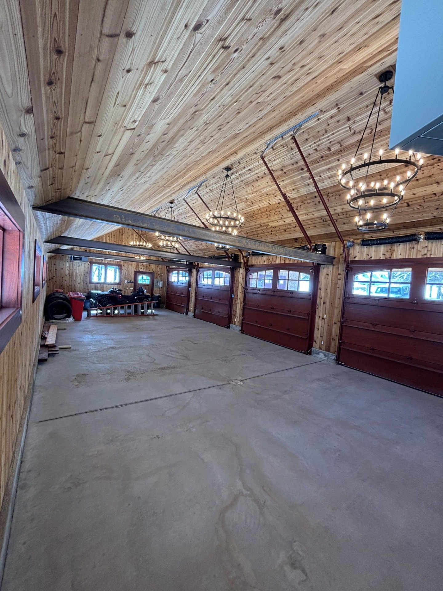 Covered outdoor venue with wooden ceiling, chandeliers, and large open concrete floor