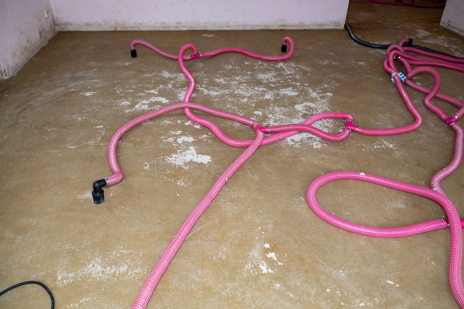 Water extraction hoses spread across a wet floor during indoor flooding cleanup and restoration work