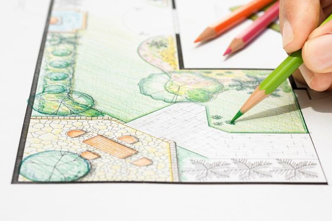 Hands sketching a colorful landscape plan with pencils on paper