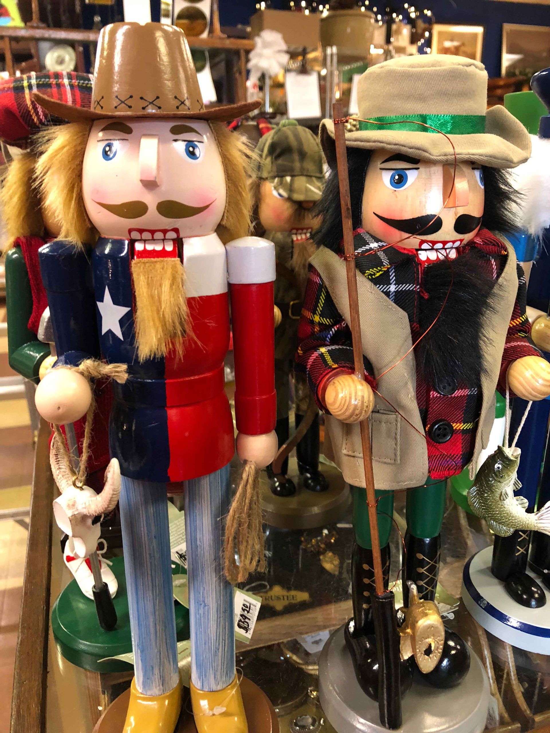 Two festive nutcracker figurines in hats, one with a star-spangled outfit, displayed on a shelf.