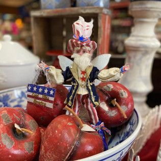 Decorative Uncle Sam figurine among red apples in a blue-and-white bowl