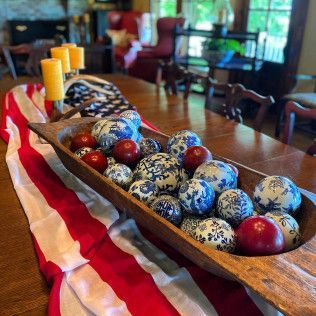 Decorated bowl of blue and red eggs on a red-and-white cloth in a dining room