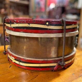 Small red, cream, and black drum with a translucent center on a wooden table.