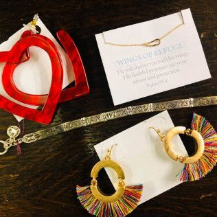Jewelry display with red heart earrings, multicolor hoop earrings, and a bracelet on a dark wooden surface