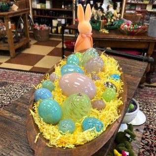 Colorful Easter eggs in a wooden boat with yellow filler and a pink bunny figure in a shop display