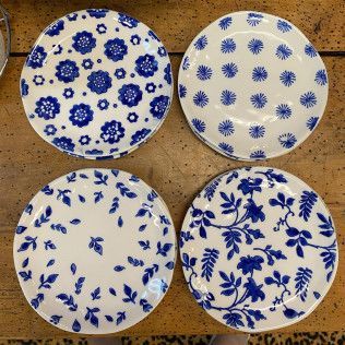 Four blue-and-white floral ceramic plates arranged in a 2x2 grid on a tan surface