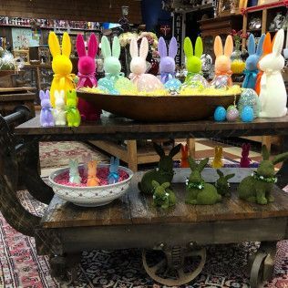 Colorful bunny figurines and Easter decorations arranged on a rustic wooden cart indoors