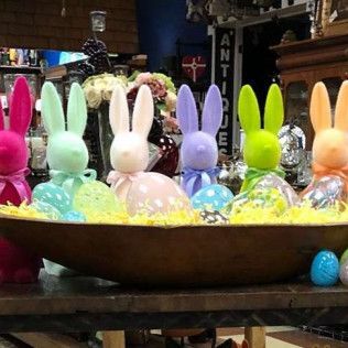 Colorful bunny figurines in a bowl with pastel Easter eggs and decorations